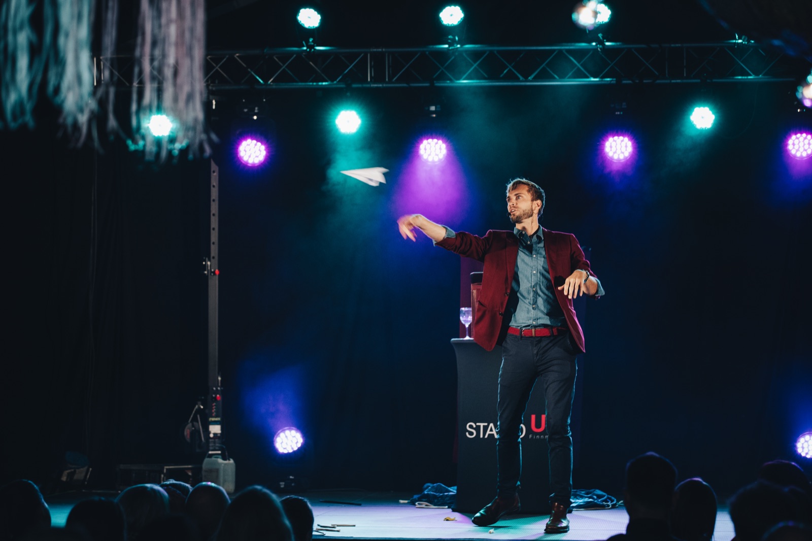 Hans Grane på scenen med et papirfly over publikum under et sceneshow